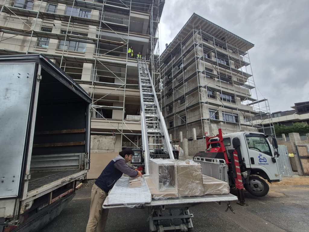 İnşaat cephesinde yükselen asansör ve platformdaki yapı malzemeleri